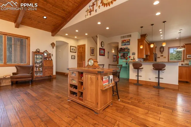 a living room with couches and kitchen view with wooden floor