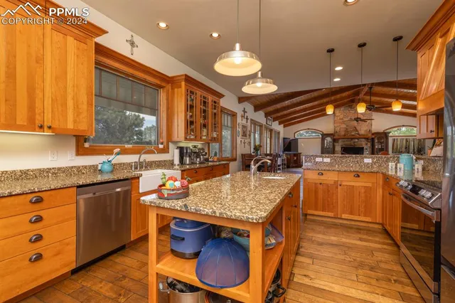 a kitchen with stainless steel appliances granite countertop a sink a stove and a wooden floors