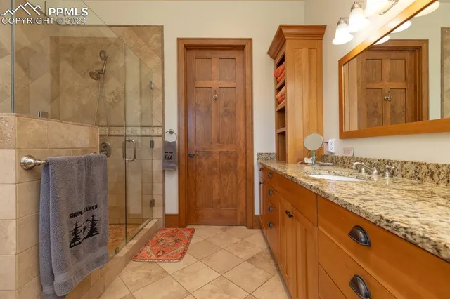 a bathroom with a granite countertop sink a mirror and shower
