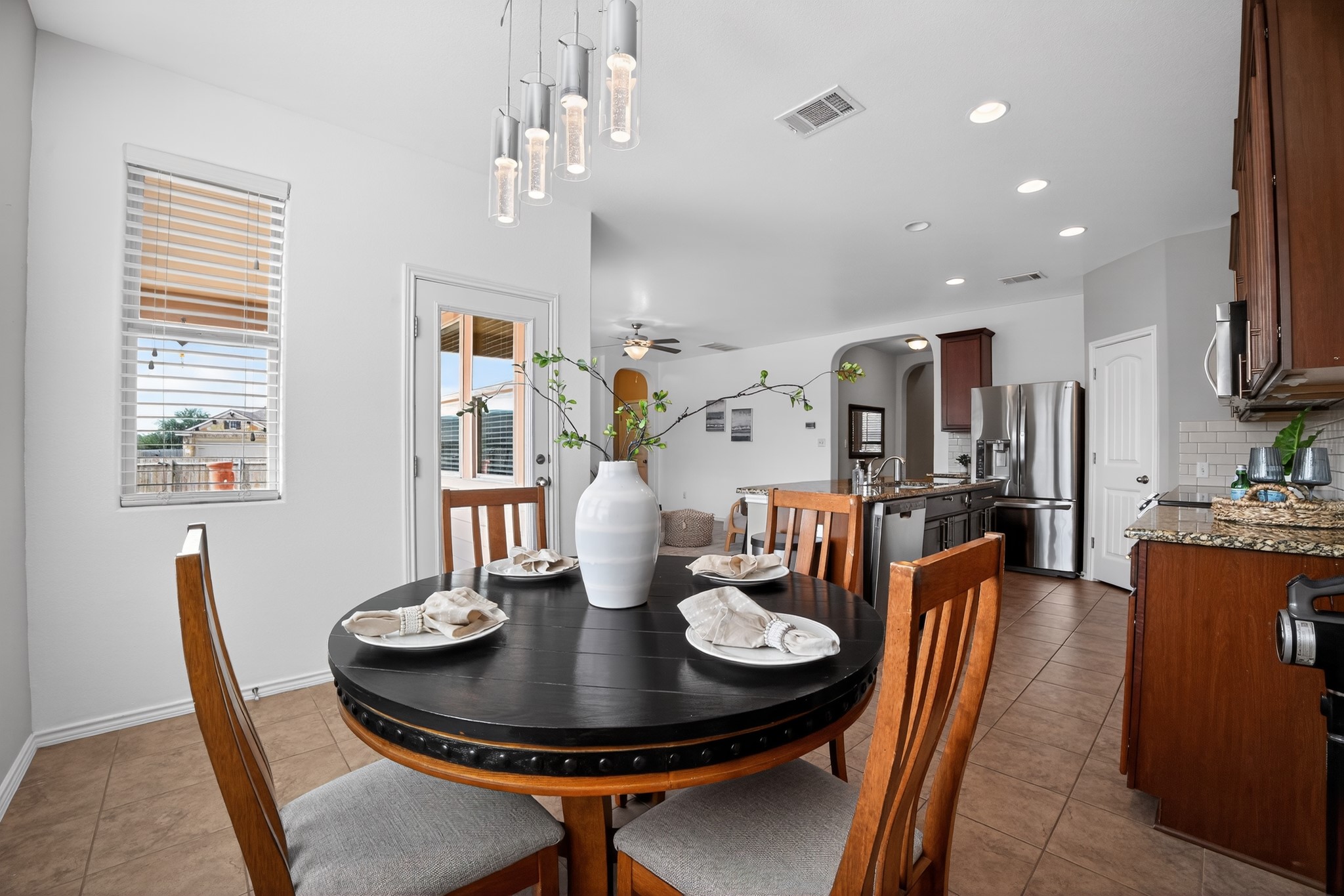 16816 Ruggio Road Pflugerville, TX 78660 - Photo 7 of 30 A casual dining space flows into a contemporary kitchen, illuminated by both natural light and elegant fixtures.