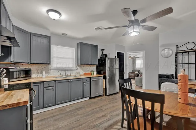 a kitchen with cabinets a sink appliances and chairs