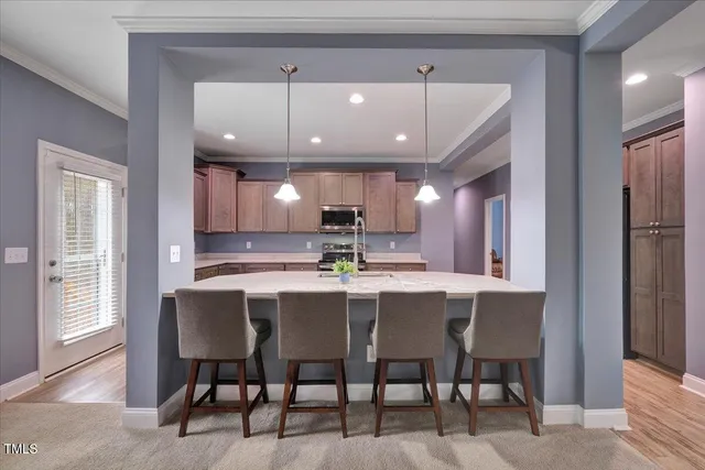 a kitchen with stainless steel appliances a dining table chairs and wooden floor