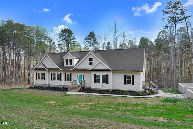 a front view of a house with a garden and trees