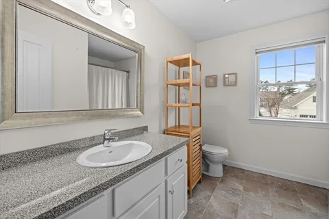 a bathroom with a granite countertop sink a toilet and a mirror