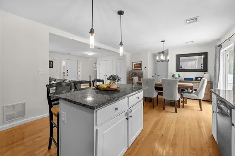 a kitchen with stainless steel appliances granite countertop a sink a stove top oven a counter space and wooden floor