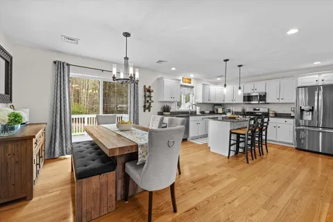 a dining room with stainless steel appliances kitchen island granite countertop a dining table chairs and white cabinets