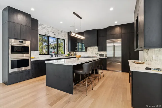 a large kitchen with stainless steel appliances a large counter top a stove and a refrigerator