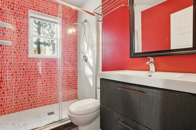 a bathroom with a sink a toilet a mirror and shower