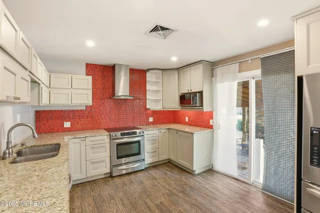a kitchen with stainless steel appliances kitchen island granite countertop a stove a sink and a refrigerator