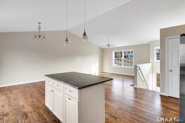 a open kitchen with kitchen island a sink dishwasher and a stove with wooden floor