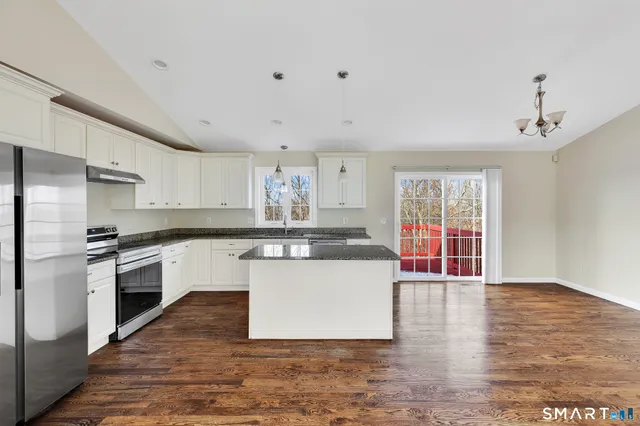 a kitchen with stainless steel appliances granite countertop a stove a sink dishwasher a refrigerator and white cabinets with wooden floor