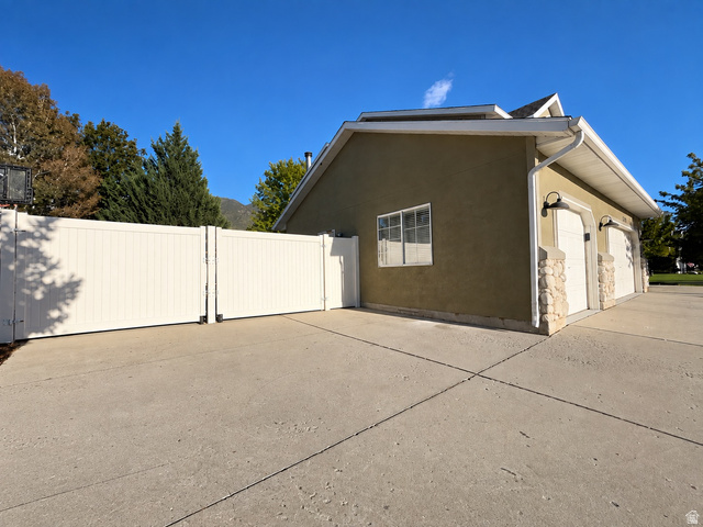 12169 Hidden Valley Road, Unit 44 Sandy, UT 84092 - Photo 46 of 49 Two-car garage with carriage-style doors, stone column accents, exterior wall sconces, and a stucco finish