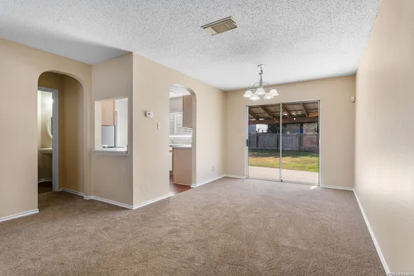 a view of an empty room with window and cabinet area