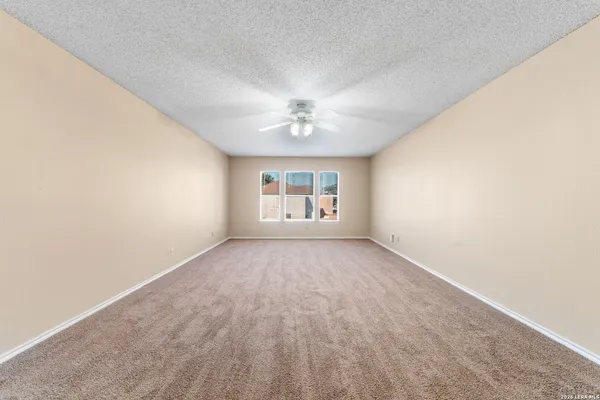 an empty room with a window and a ceiling fan