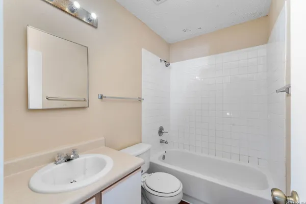 a bathroom with a bathtub shower sink vanity mirror and toilet
