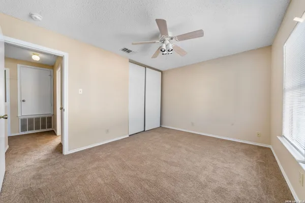 an empty room with windows and fan