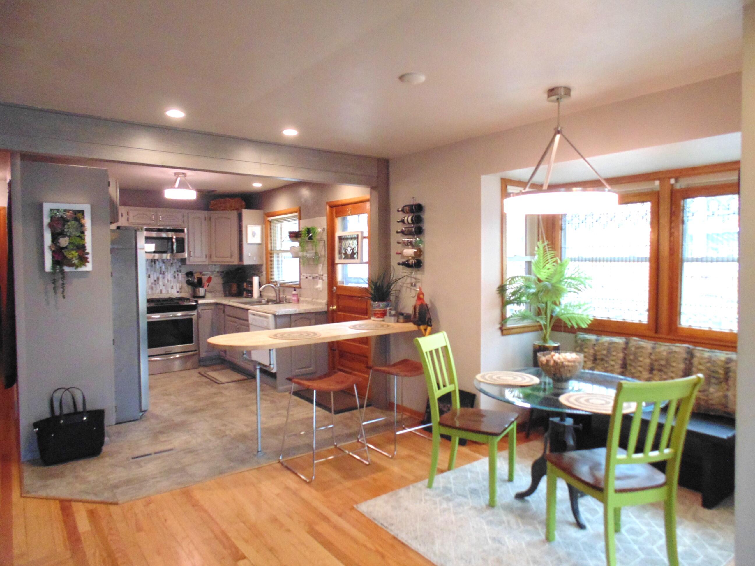 6801 Forest Avenue Gary, IN 46403 - Photo 8 of 23 a dining room with wooden floor a chandelier a wooden table and chairs