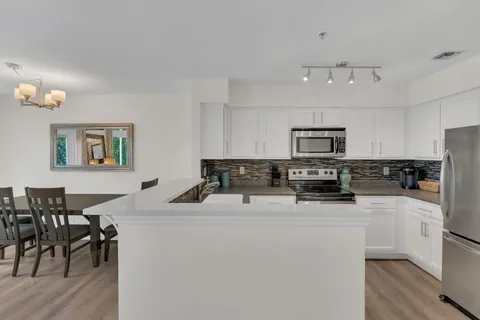 a kitchen with stainless steel appliances kitchen island a refrigerator sink and white cabinets