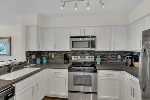 a kitchen with white cabinets and appliances