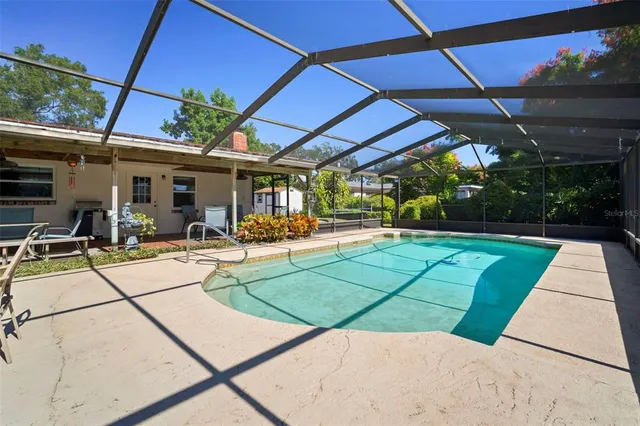 a view of a swimming pool with a patio and couches chairs