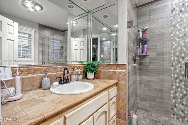 a bathroom with a granite countertop sink a mirror and shower
