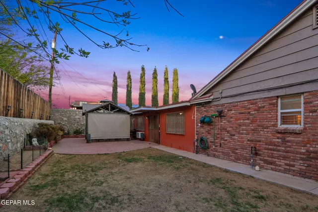 a view of a backyard with brick wall and potted plants