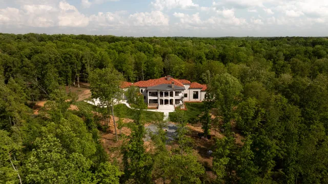 a view of a big house with a big yard and large trees