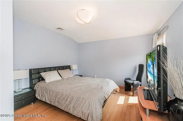 a bedroom with a bed and a flat tv screen on the dresser
