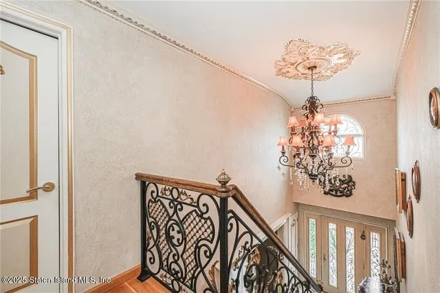 a view of a hallway with wooden floor and chandelier