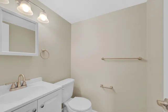 a bathroom with a toilet sink vanity and mirror