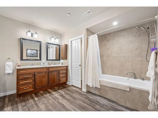 a bathroom with a granite countertop sink a mirror a bathtub and shower