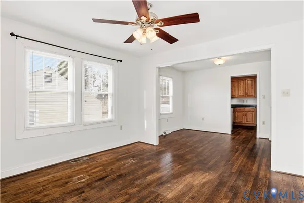 a view of an empty room with a window and wooden floor