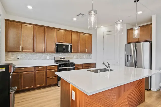 a kitchen that has a sink a microwave oven a stove and white cabinets with wooden floor