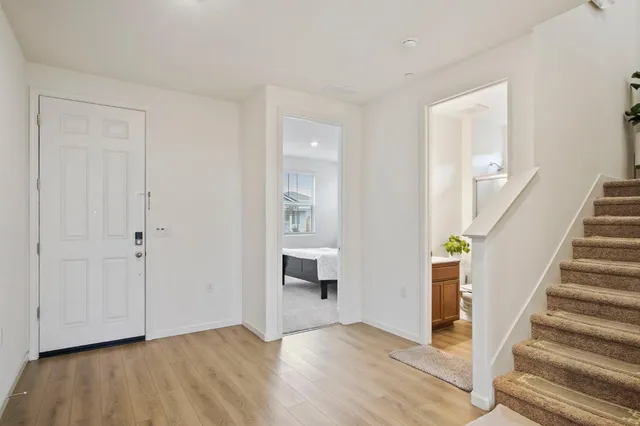 a view of an empty room with wooden floor and stairs