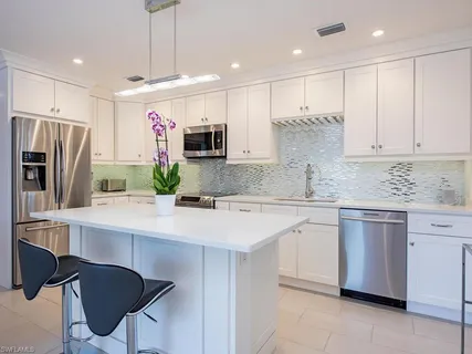 a kitchen with stainless steel appliances granite countertop a sink and a refrigerator