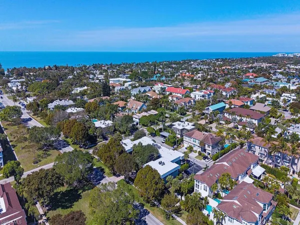 an aerial view of a city with lots of residential buildings and ocean view in back