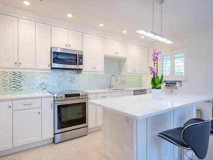 a kitchen with stainless steel appliances white cabinets a sink stove and microwave