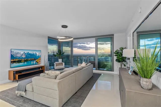 a living room with furniture kitchen view and large windows