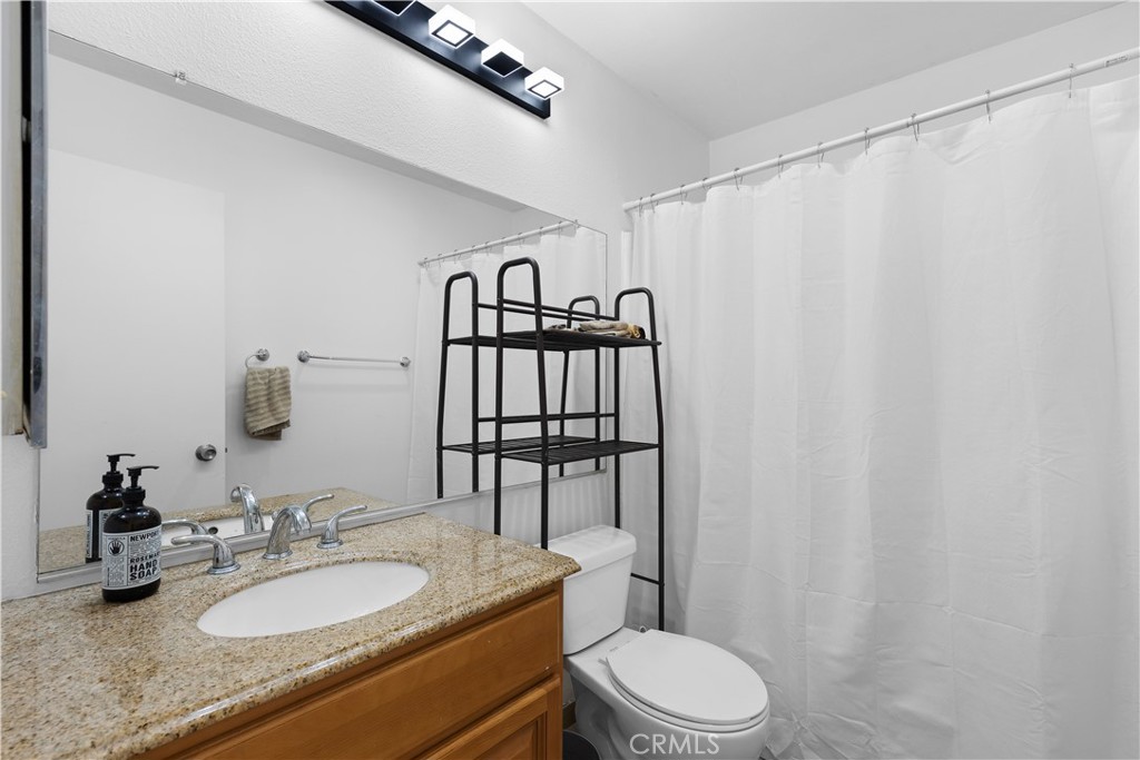 20134 Leadwell Street, Unit 332 Winnetka, CA 91306 - Photo 10 of 14 a bathroom with a granite countertop sink mirror vanity and toilet