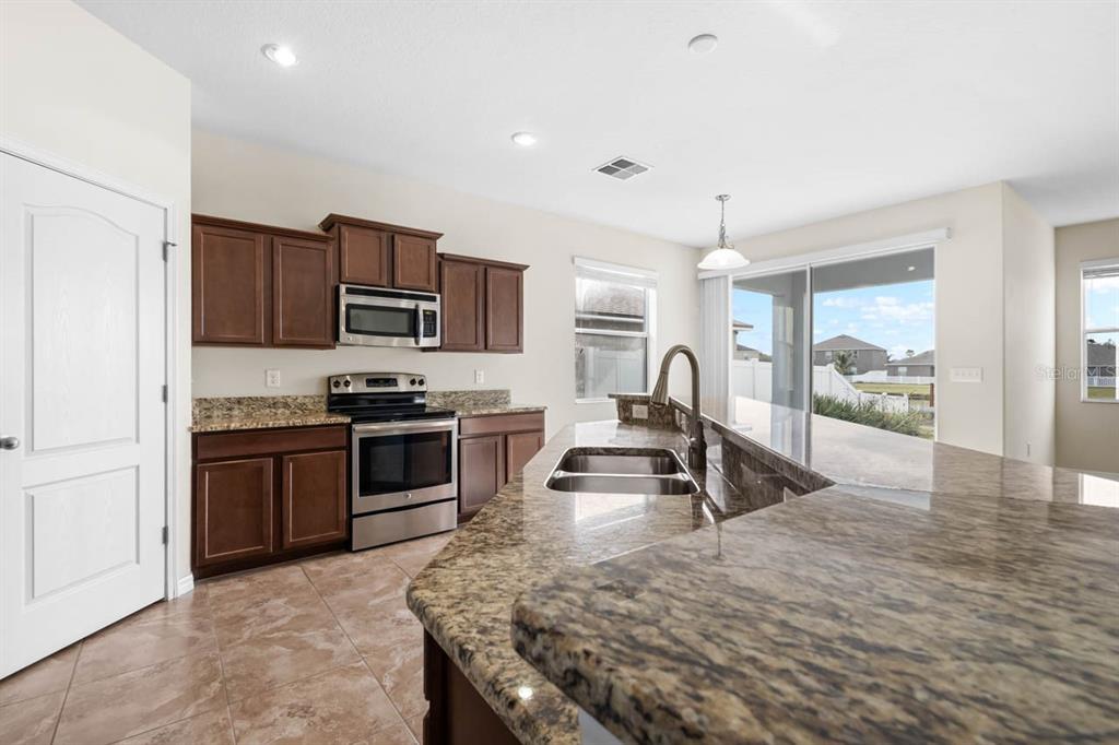1504 Oak Pond Street Ruskin, FL 33570 - Photo 16 of 76 a kitchen with granite countertop a stove and a refrigerator