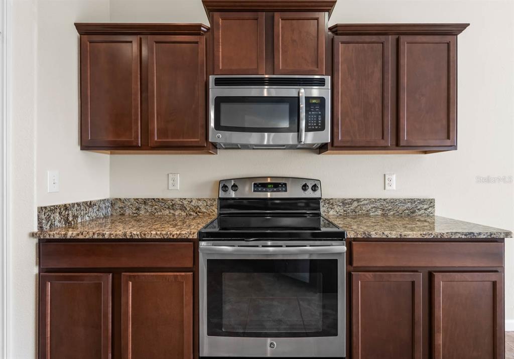 1504 Oak Pond Street Ruskin, FL 33570 - Photo 18 of 76 a kitchen with granite countertop wood cabinets and stainless steel appliances