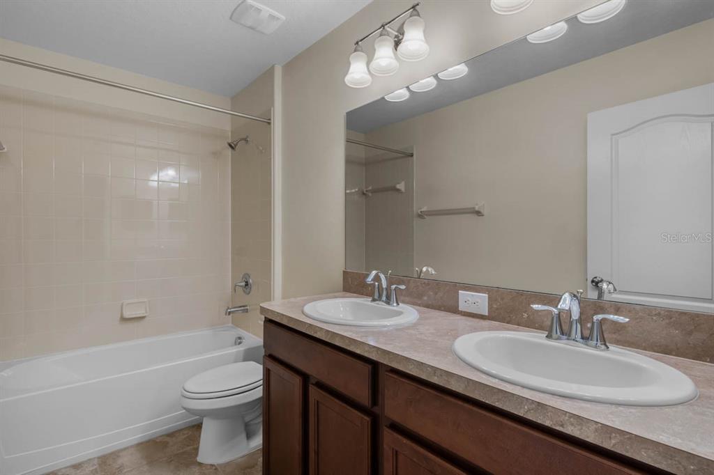 1504 Oak Pond Street Ruskin, FL 33570 - Photo 36 of 76 a bathroom with a granite countertop sink a toilet a mirror and shower