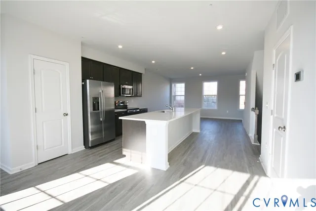 a large kitchen with a center island wooden floor stainless steel appliances and a window
