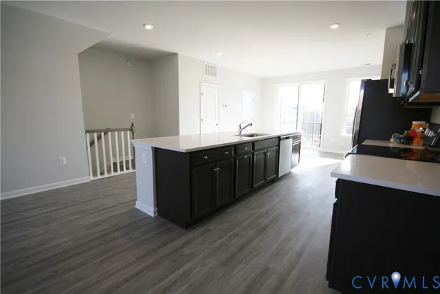 a large kitchen with wooden floor and black cabinets