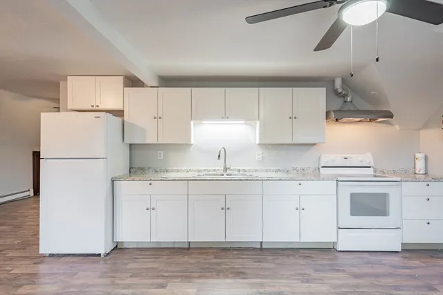 a kitchen with granite countertop white cabinets and white appliances