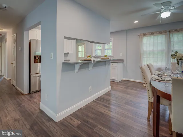 a kitchen with stainless steel appliances granite countertop a refrigerator a sink dishwasher a stove and white countertops with wooden floor