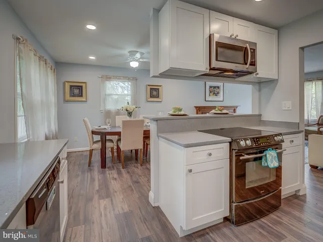 a kitchen with a stove top oven a sink dishwasher a dining table and chairs with wooden floor
