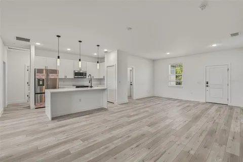 a view of kitchen with kitchen island white cabinets wooden floor and stainless steel appliances