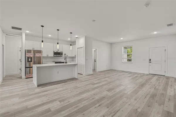 a view of kitchen with kitchen island white cabinets wooden floor and stainless steel appliances