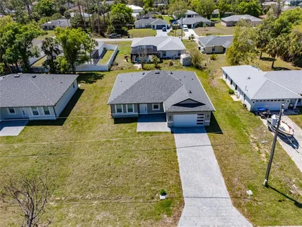 an aerial view of a house with swimming pool and large trees